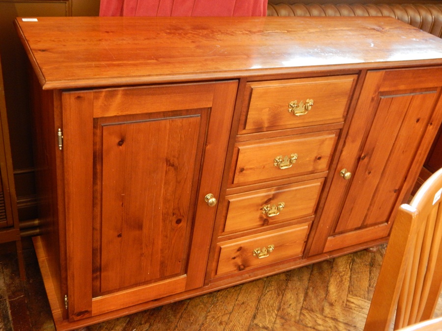 A contemporary sideboard with four central short drawers flanked by a pair of cupboards on bun feet,