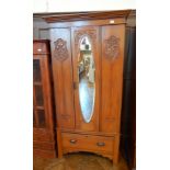 A late Victorian satin walnut wardrobe with oval mirror door, enclosing hanging space, drawer below,