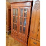 An Eastern hardwood glazed bookcase with pair panel doors enclosing shelves,