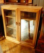 A modern elm display cupboard, the pair of double glazed panel doors enclosing shelves,