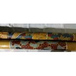 A didgeridoo carved with snake entwined with tribal decoration together with a rain stick with