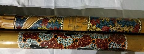 A didgeridoo carved with snake entwined with tribal decoration together with a rain stick with