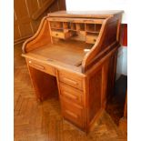 An oak tambour top desk with single drawer and three graduated drawers,