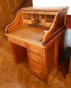 An oak tambour top desk with single drawer and three graduated drawers,