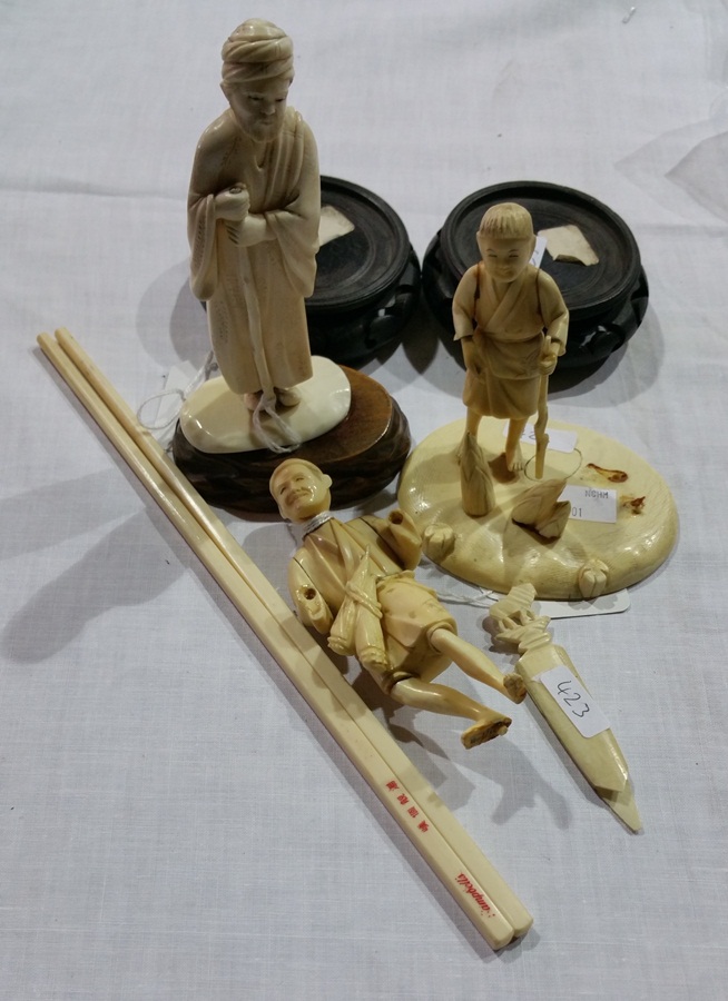 Three Japanese carved ivory male figures and chopsticks with stands