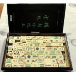 A mahjong set in a hardwood case with Oriental writing on the front