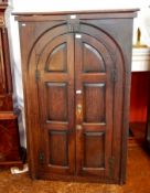 18th century oak corner cupboard, the arched panel doors enclosing shelves,