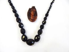 String of red amber type faceted and graduated beads and carved amber cameo,