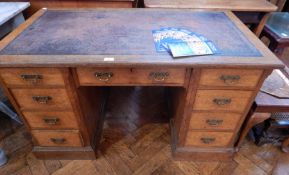 An oak kneehole writing desk with inset leather top, four drawers either side and one frieze drawer,