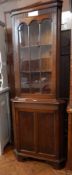 A reproduction oak corner cupboard, the astragal glazed door enclosing shelves,