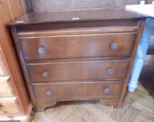 An oak chest of drawers with floral and scroll brass handles, on bracket supports,