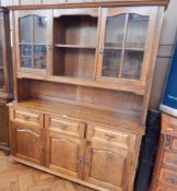 A reproduction oak dresser, the back with open shelf flanked by a pair of glazed cupboards,
