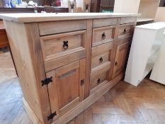 A contemporary pine dresser base, with five short drawers and panelled cupboards, on a plinth base,