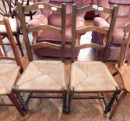 A pair of stained beech ladder back occasional chairs with rush seats,