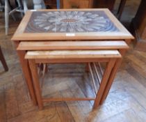 A nest of three oak tables with tiled tops