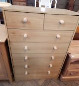 A melamine chest of drawers with two short and five long drawers, turned handles,