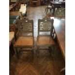 A set of six limed oak dining chairs with foliate carved panel backs and cane seats on carved