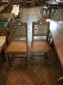 A set of six limed oak dining chairs with foliate carved panel backs and cane seats on carved