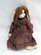 An antique painted papier mache and cloth doll with painted features, real hair,