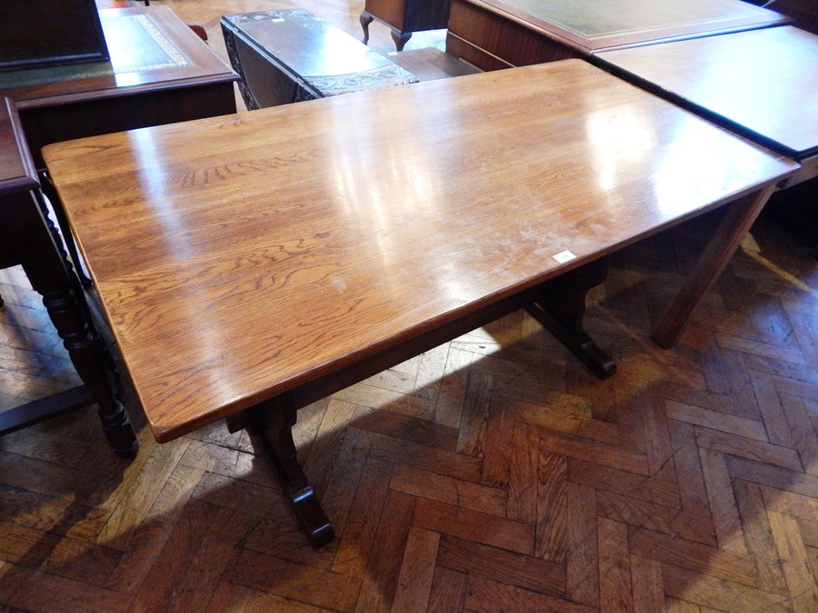 An oak rectangular top dining table, on twin trestle supports united by central stretcher,