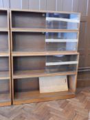 A modern hardwood bookcase with glazed sliding doors, raised on plinth base,