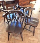 A set of four stained beech dining chairs, with curved backs supported by turned spindle splats,