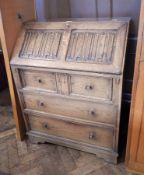 A reproduction carved oak bureau, the fall with linenfold carved panels, three drawers below,