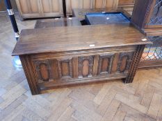 A reproduction oak coffer, with arcaded carved front, on reeded style supports,