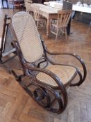 A bentwood rocking chair with caned panelled back and seat