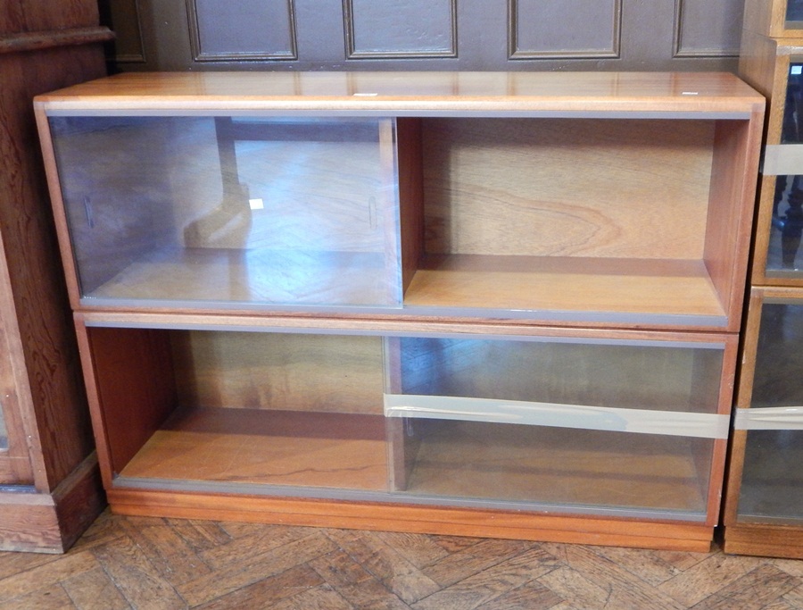 A modern hardwood bookcase of four shelves with glazed sliding doors,