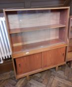 A circa 1960's bookcase with glass sliding doors, cupboard below, raised on turned tapering legs,