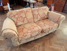 A two seater sofa with floral russet upholstery, loose cushion back and seats, with arm protectors,