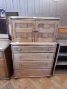 A reproduction panelled oak cupboard, with four long drawers below raised on bun feet,