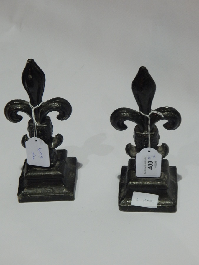 Two cast iron Fleur de Lys decorative models and two similar pine cone-shaped