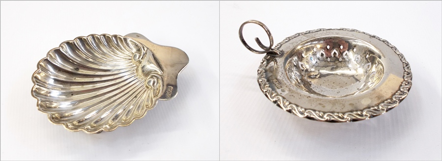 Silver scallopshell pattern butter dish on ball feet, London 1910 together with silver tea strainer,