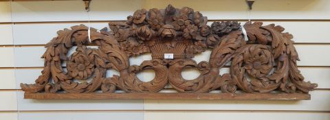 Carved oak pediment with floral and scroll design centred by floral display and eagle head supports,