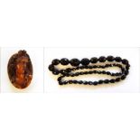 String of red amber type faceted and graduated beads and carved amber cameo,