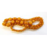 Carved and polished yellow amber coloured bead necklace having graduated oval carved beads with