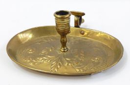 Georgian brass chamber candlestick, the oval tray repousse with scrolling leaves,