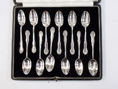 Set of twelve George V silver teaspoons with foliate embossed and wavy bordered handles,