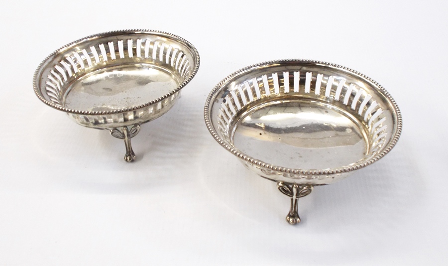 Pair of George V silver bonbon dishes with reed borders, openwork design, raised on toed feet,