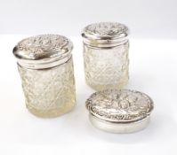 Pair of George V silver-capped cut glass dressing table jars with cherub head decoration,