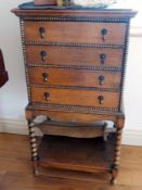 A 1920's oak four-drawer music cabinet on bobbin turned supports and work undertier,