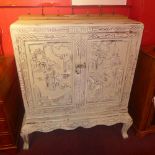 A Chinese painted distressed finish side cabinet with profusely carved decoration in relief fitted