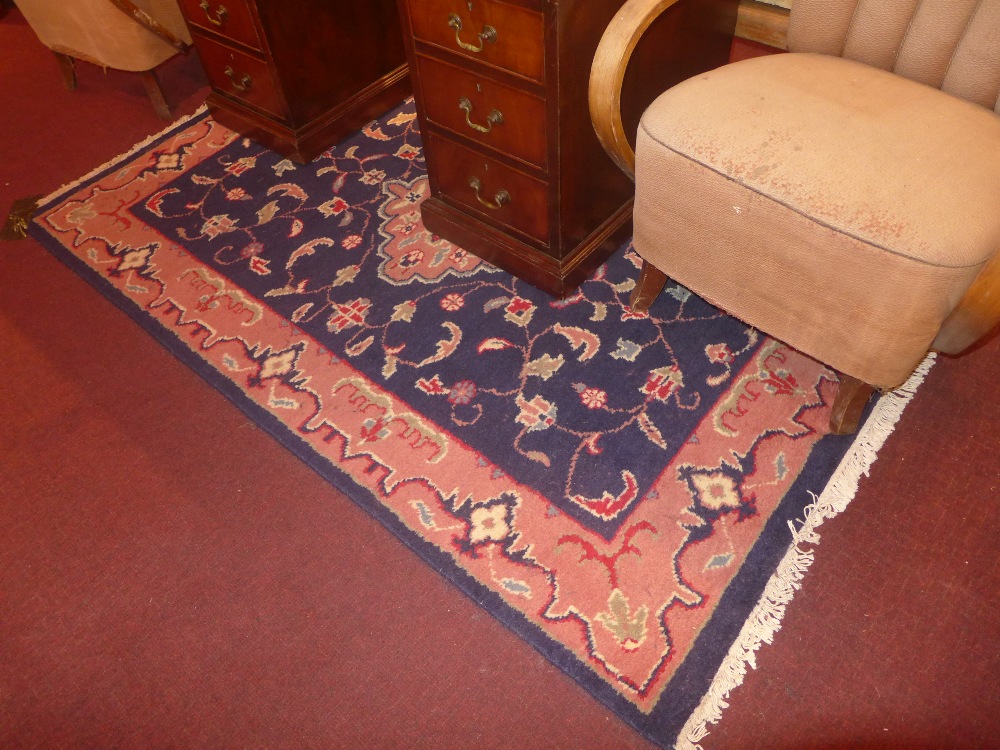 A handmade Persian rug with a central medallion on a midnight blue field surrounded by a frieze