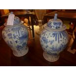 A pair of Chinese blue and white lidded temple jars decorated with fish and water lilies