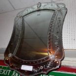 An early C20th Venetian looking glass the shaped plate within bevelled edge frame with etched flower