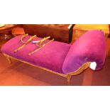 An antique chase longue, upholstered in purple velour with an ornate giltwood frame raised on carved