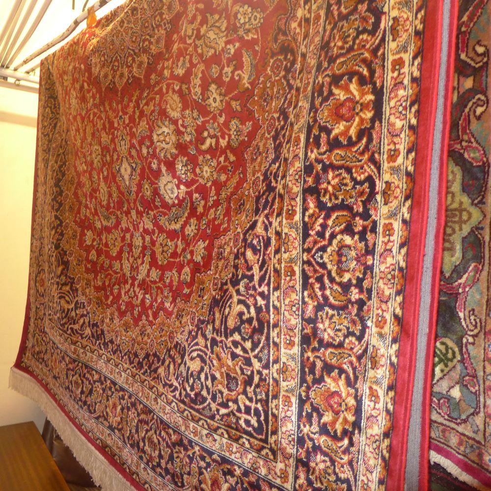 A Keshan design carpet with a flowerhead medallion on a red field with a floral design surrounded