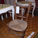 A childs pine chair with rush seat (one stretcher missing)